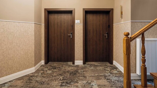 A hallway with two wooden doors, a carpeted floor, and a wooden staircase. - White Lotus - penthouse with roof terrace (Kraków)