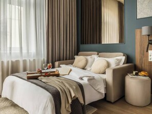 Ein Schlafzimmer mit einem Bett, einem Sofa, einem Nachttisch und einem Fenster mit Vorhängen.