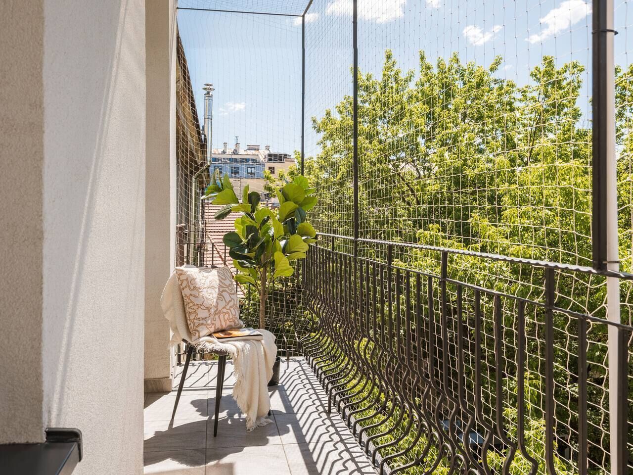 A balcony with a chair, a table, and a metal fence.