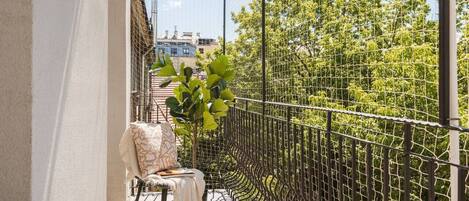 A balcony with a chair, a table, and a metal fence.