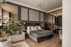 A bedroom with a large bed, a sofa, a mirror, and a chandelier. - White Lotus - 2-bedroom, living room (Kraków)
