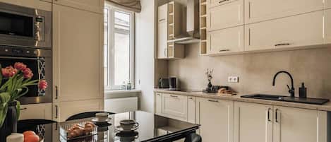 A modern kitchen with a dining area, featuring a built-in oven, a microwave, a sink, and a window with a view.
