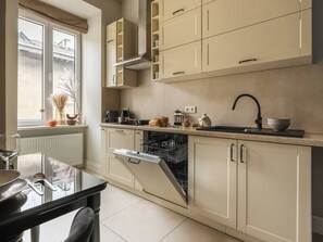 A modern kitchen with a dishwasher, a sink, and a window with a view of a building. - White Lotus - 2-bed apartment, full kitchen (Kraków)