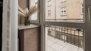 Una ventana con vistas a un edificio y un balcón con barandilla de metal.
