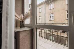A window with a view of a building and a balcony with a metal railing. - White Lotus - studio with balcony (Kraków)