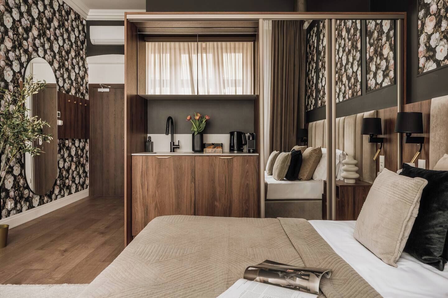 Un dormitorio con cama, mesita de noche, espejo, armario, tocador y ventana con cortinas.
