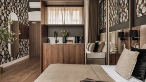 Un dormitorio con cama, mesita de noche, espejo, armario, tocador y ventana con cortinas.