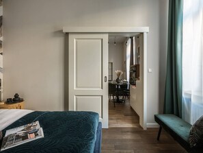 A bedroom with a bed, a bench, a desk, and a dining area. - Green Boho 2-bed family apt in the city center (Kraków)