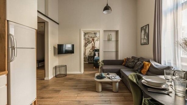 A modern living room with a sofa, coffee table, and dining area. - Green Boho 2-bed family apt in the city center (Kraków)