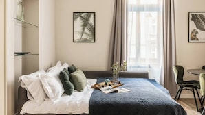 A neatly made bed with pillows, a tray with items, and a framed picture on the wall. - Green Boho 2-bed family apt in the city center (Kraków)