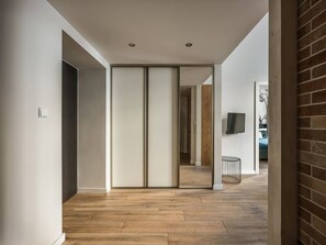 A hallway with wooden flooring, a sliding door, and a brick wall. - Green Boho 2-bed family apt in the city center (Kraków)