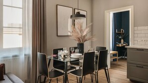 Zona pranzo moderna con tavolo in vetro, sedie nere e lampada a sospensione.