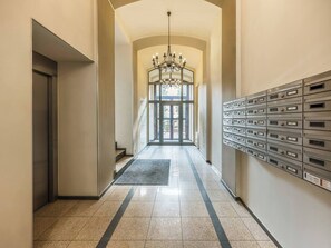 A hallway with a chandelier, mailboxes, and a door leading to a bright room. - 2-bedroom Boho apartment in the heart of Kazimierz (Kraków)