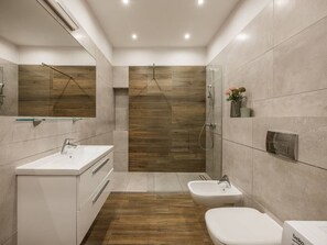 Et moderne badeværelse med bruser, bidet og et spejl med underskab.