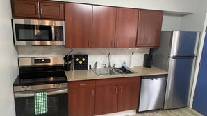 Una cocina moderna con electrodomésticos de acero inoxidable, gabinetes de madera y encimera de granito, además de un lavavajillas.