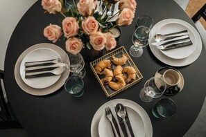 A round dining table with plates, cutlery, glasses, and a box of pastries. - Skawińska 2-bed apartment on the ground floor (Kraków)