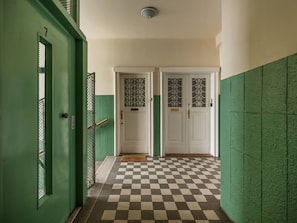 A hallway with green walls, checkered floor, and double doors with decorative glass panels. - Iconic Sunset Penthouse 115 sqm (Kraków)
