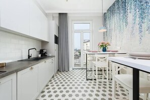 Una cocina moderna con armarios blancos, encimera gris y suelo con patrón hexagonal.