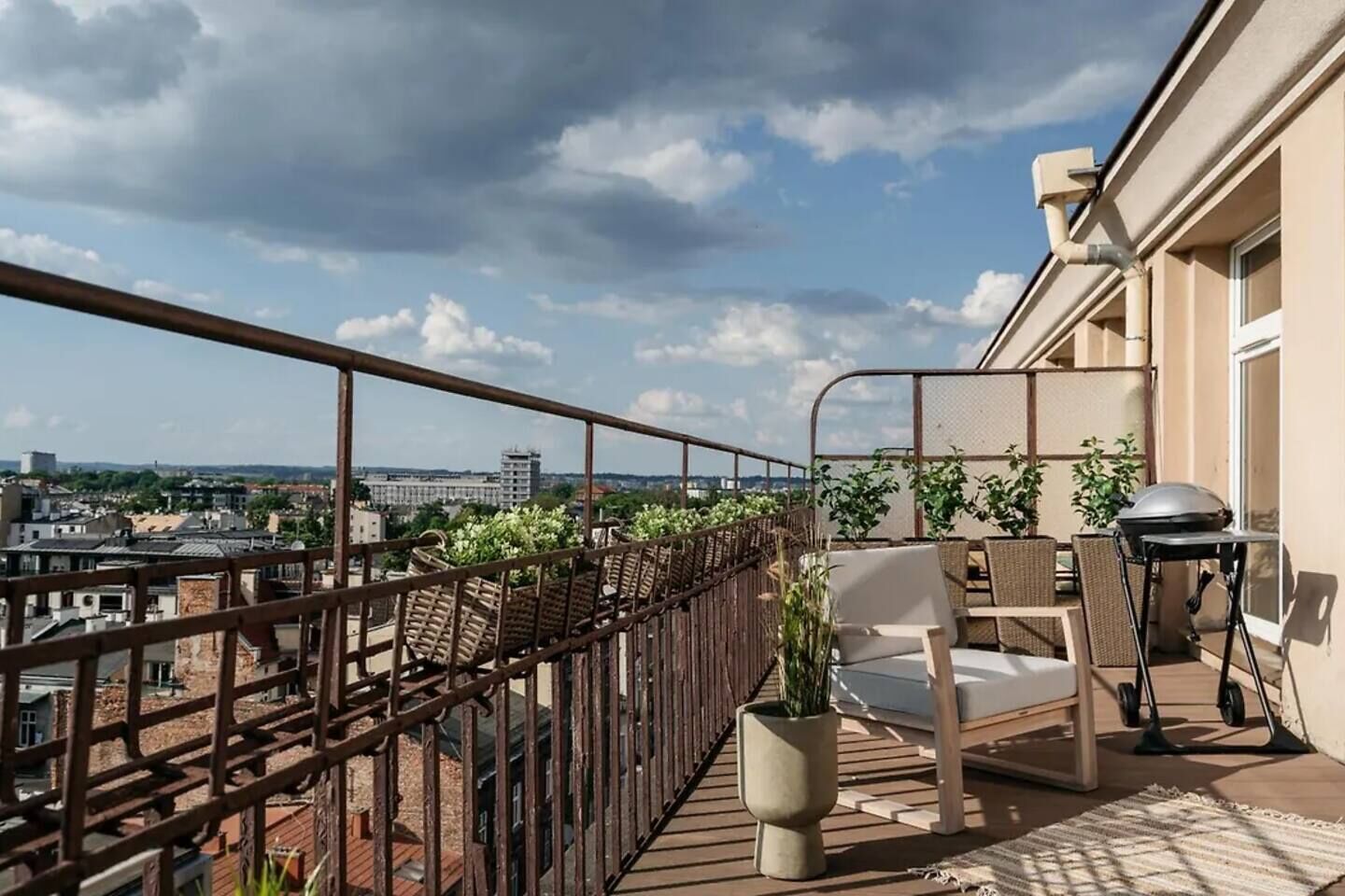 Un balcón con vistas a la ciudad, una parrilla y mobiliario exterior.