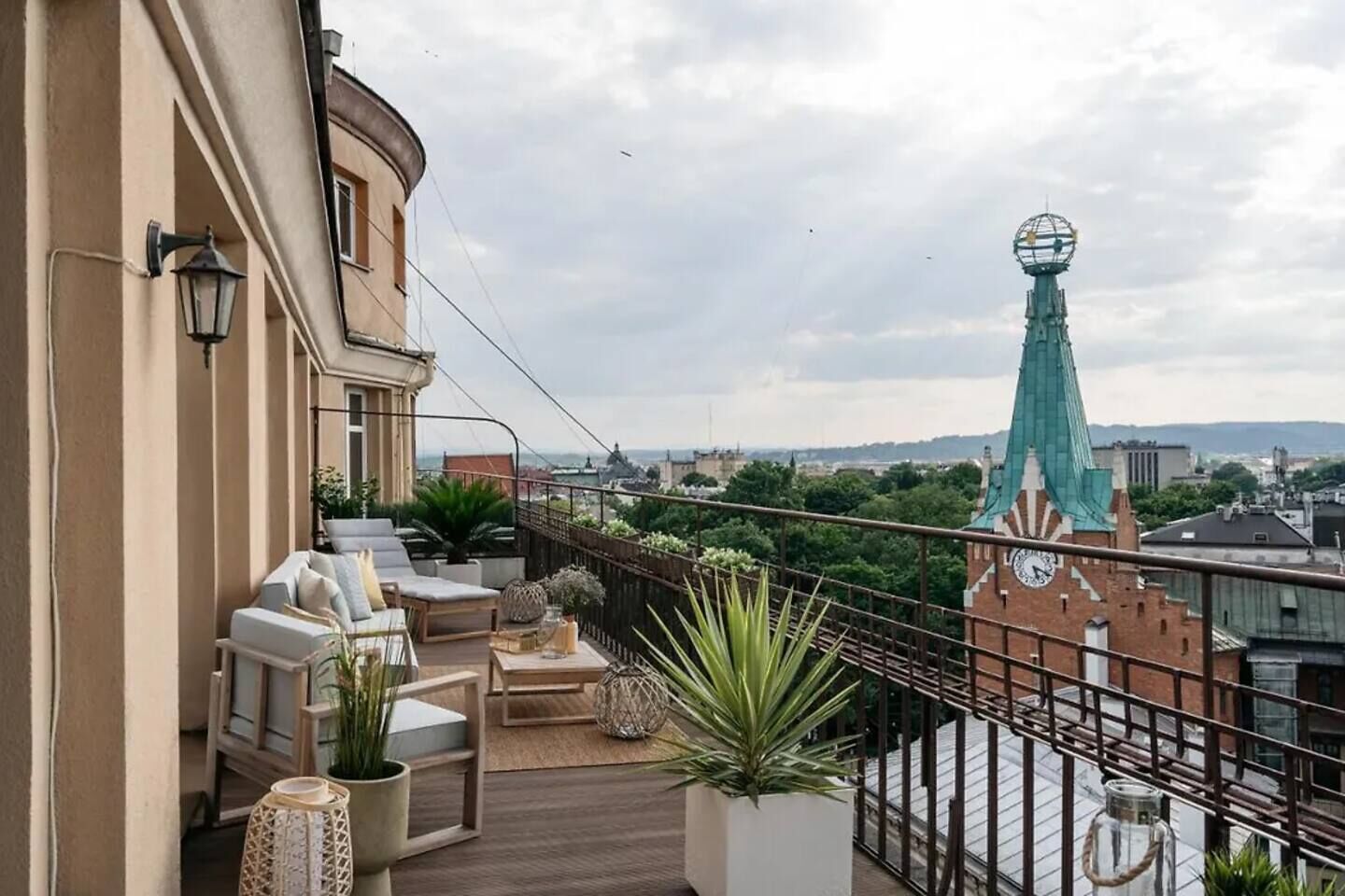 Un balcón con mobiliario exterior, una torre del reloj y vistas a la ciudad.