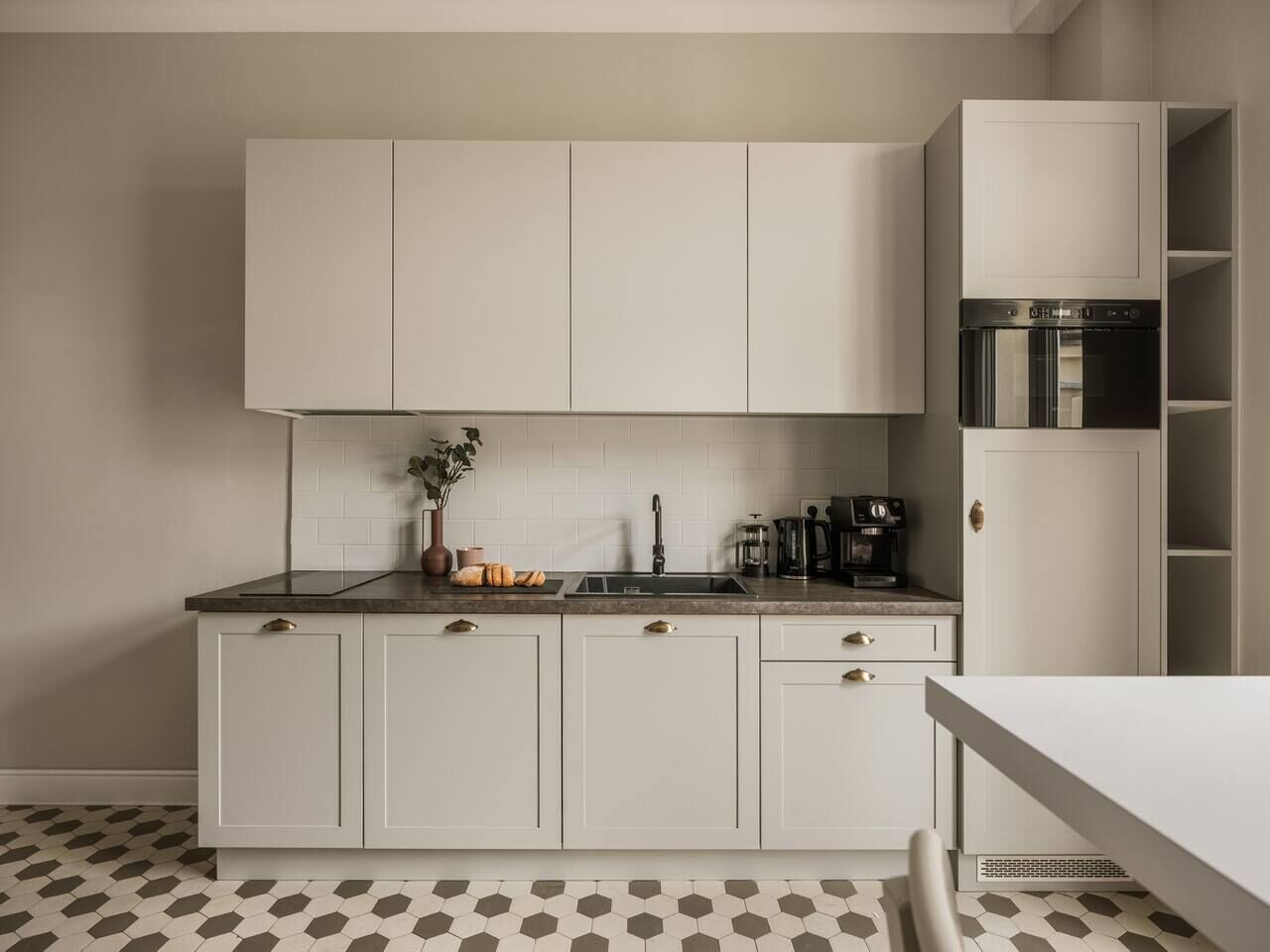 A modern kitchen with white cabinets, a black countertop, and a coffee maker.