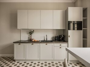 A modern kitchen with white cabinets, a black countertop, and a coffee maker. - Iconic Sunset Penthouse 115 sqm (Kraków)