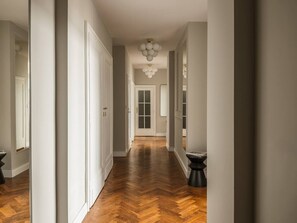 A hallway with a herringbone floor, white walls, and a door at the end. - Iconic Sunset Penthouse 115 sqm (Kraków)