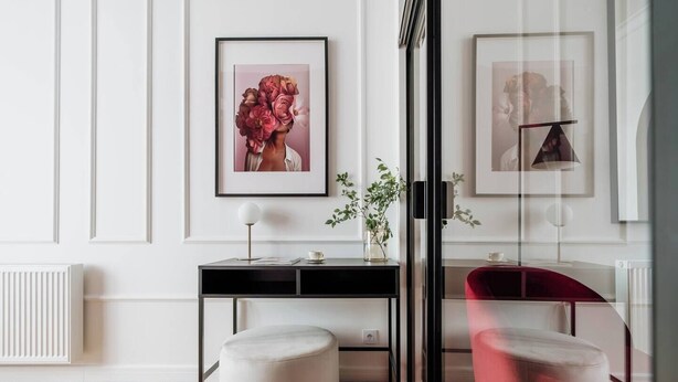A modern room with a black desk, two round ottomans, a glass partition, and framed artwork on the wall. - 3-bedroom apartment Merlot (Kraków)