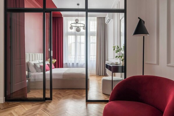 A bedroom with a bed, a desk, a chair, and a red armchair. - 3-bedroom apartment Merlot (Kraków)