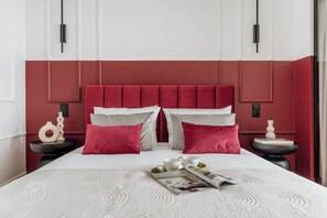A bed with a white bedspread, two red pillows, and a magazine on the bed. - 3-bedroom apartment Merlot (Kraków)