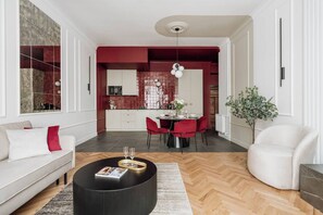 A modern living room with a sofa, a dining table with chairs, a coffee table, and a potted plant. - 3-bedroom apartment Merlot (Kraków)