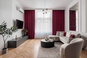 A modern living room with a sofa, coffee table, and a TV on the wall. - 3-bedroom apartment Merlot (Kraków)