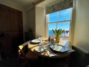 A dining table set for two with a view of the ocean through a window. - Sma' Gift- Seafront sanctuary in ST Monans (Saint Monans)