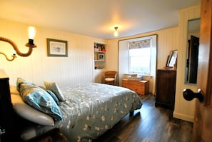 Une chambre à coucher avec un lit, une chaise, une commode et une fenêtre.