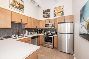 A modern kitchen with stainless steel appliances, wooden cabinets, and a white countertop. - Downtown Cincinnati | 2 Suites | Sleeps 6 (Cincinnati)