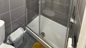 A modern bathroom with a glass-enclosed shower, a toilet, and a trash bin. - Double Bedroom with Attached Bathroom in Blackpool-Families and Couplies Only (Blackpool)