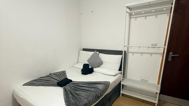 A single bed with a grey blanket and pillows, a wooden floor, and a wardrobe with a mirror. - Double Bedroom with Attached Bathroom in Blackpool-Families and Couplies Only (Blackpool)