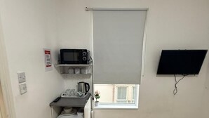 A small kitchen with a microwave, a small fridge, and a window with a view. - Double Bedroom with Attached Bathroom in Blackpool-Families and Couplies Only (Blackpool)