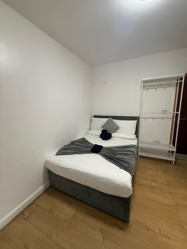 A neatly arranged bedroom with a bed, a bedside table, and a wardrobe.
