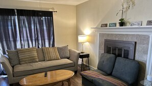 Una sala de estar con sofá, sillón, mesa de centro, lámpara y chimenea.