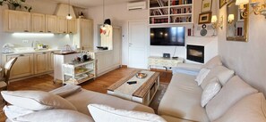 Un salon moderne avec un canapé, une table basse et un téléviseur. Il y a également un coin cuisine avec des placards et une table à manger.