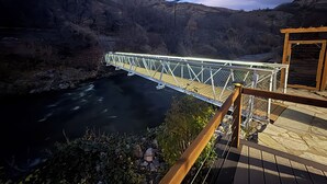 A metal bridge over a river with a wooden deck and railing on the right.