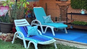 Une terrasse avec deux chaises longues blanches, une petite table et une plante en pot.