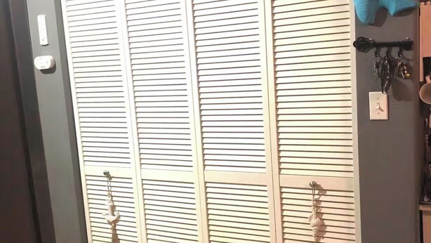 Une porte fermée, avec une pancarte « LAVERIE-SÉCHERIE » au-dessus, un porte-clés et un petit objet décoratif accroché au mur.