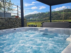Un bain à remous avec vue sur un paysage verdoyant et des collines en arrière-plan.