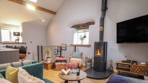 A cozy living room with a fireplace, a television, and comfortable seating. - The Old Cartshed Yr Hen Gwt Cart (Abergele)