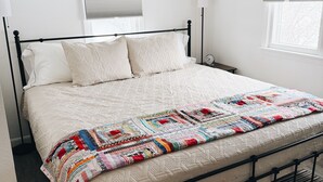 A neatly made bed with a quilt, a bedside lamp, and a clock on the nightstand. - Cozy 2-Bedroom Hulett Home Near Devils Tower & Black Hills (Hulett)