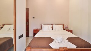 Une chambre d’hôtel avec un grand lit, une tête de lit en bois, une table de chevet avec une lampe et une porte de salle de bain.