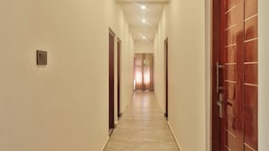 Un couloir avec un sol carrelé, des portes en bois et un luminaire au plafond.
