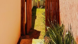 A narrow pathway leading to a building with a thatched roof and a wooden fence.